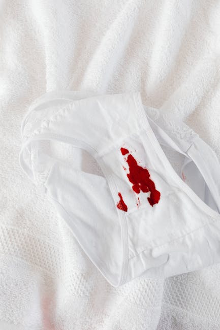 A white fabric surface, possibly a bedsheet or curtain, with a white cloth featuring a red stain, suggests a spill that requires surface cleaning and stain removal. The fabric appears soft, with a textured pattern visible in the background. The lighting is bright and even, highlighting the contrast between the clean white material and the red stain, emphasizing the need for professional deep cleaning or sanitisation. This image relates to the services offered by Merton Park Carpet Cleaners, highlighting the importance of prompt and effective stain removal to maintain hygiene and cleanliness in residential or commercial spaces.